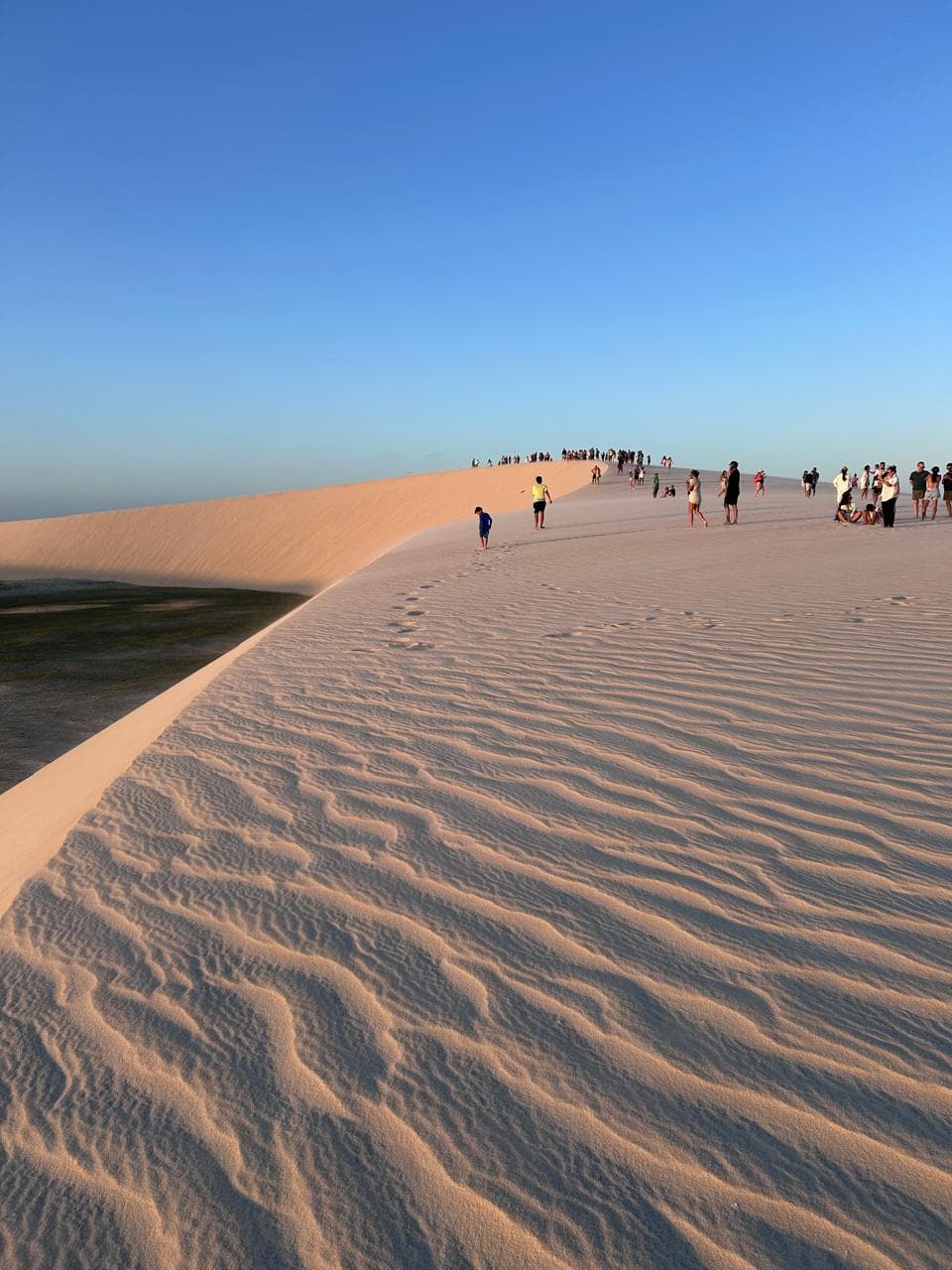 Duna extensa ao entardecer com pessoas ao longe